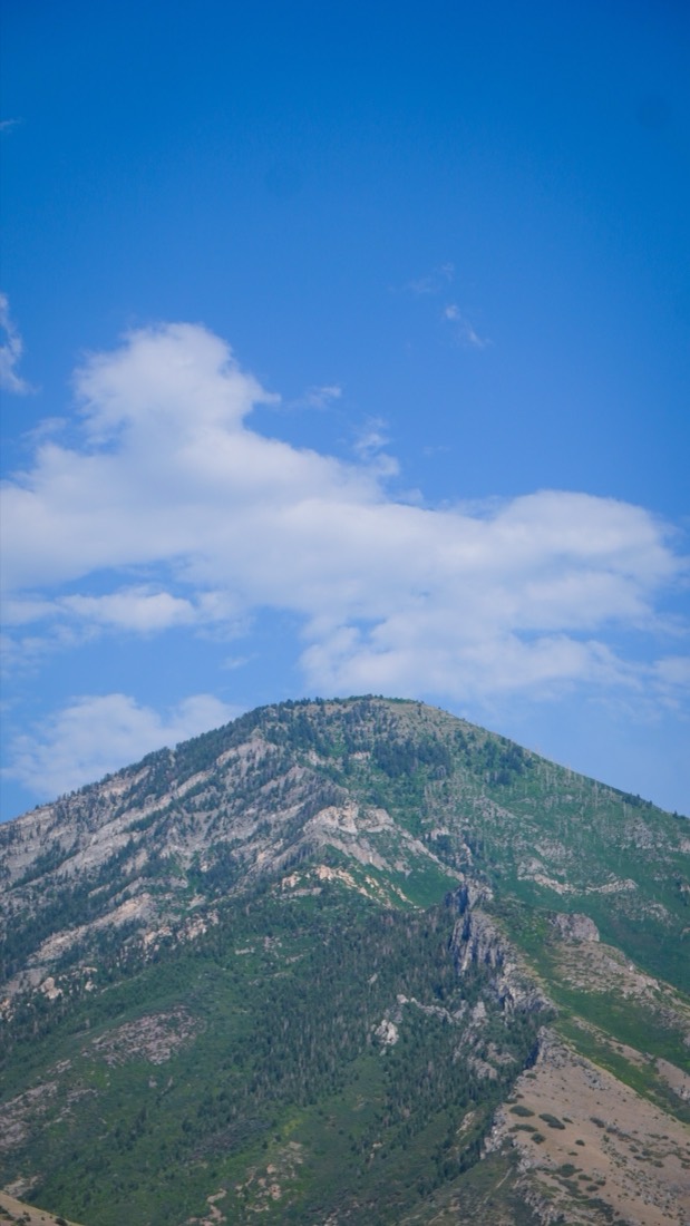 A rocky peak rising into white clouds and blue sky